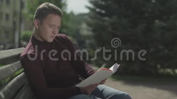 年轻人合上一本书从长凳上站起来视频的预览图