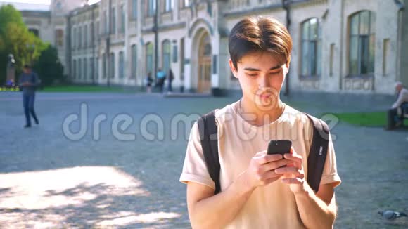 斯迈利快乐的亚洲人正在使用他的智能手机交流站在街上城市的情绪舒适的阳光明媚的地方视频的预览图
