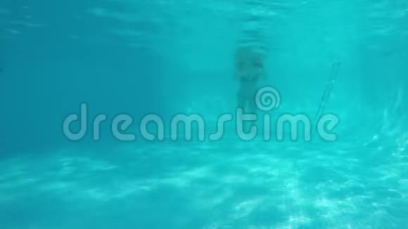 穿着蓝色比基尼的白人女孩在蓝色游泳池的镜头下游泳从水下观看视频的预览图
