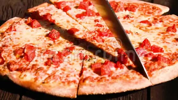 一个人将意大利香肠比萨饼切成多片的特写镜头视频的预览图