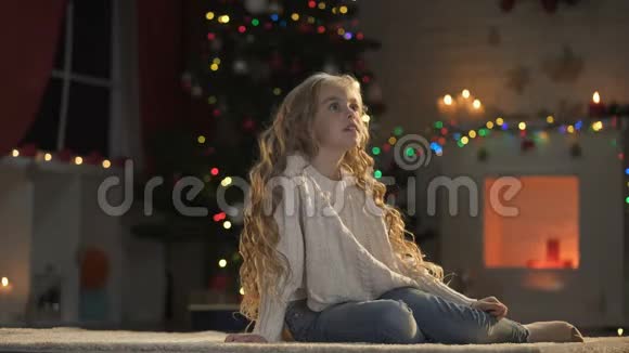 女孩坐在地板上装饰着圣诞节等待圣诞老人节日魔术视频的预览图