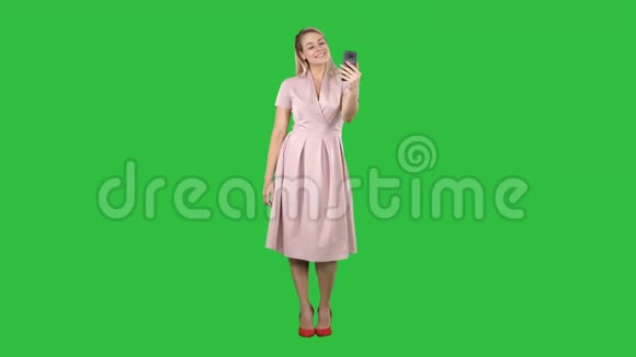 成熟的女人穿着淡粉色连衣裙在绿色屏幕上自拍Chroma键视频的预览图