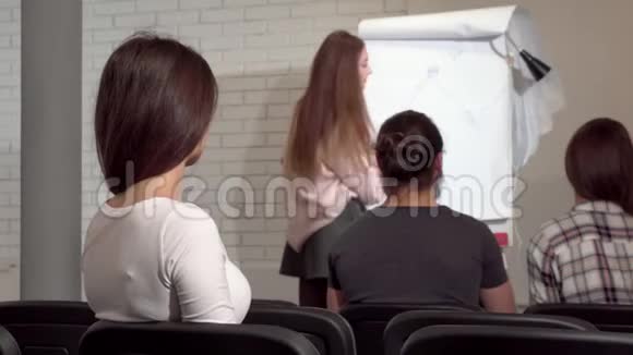 一个女商人在商业会议上听一个演讲者的后视镜头视频的预览图