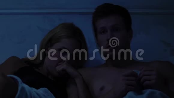 一对夫妇躺在床上看电视上的恐怖片晚上在一起视频的预览图