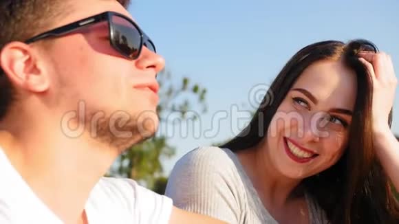 一对年轻快乐的夫妇的肖像浪漫的情侣在蓝天上聊天和坐着一起快乐关门视频的预览图