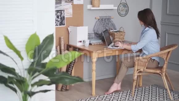 设计师在家庭工作室工作穿休闲装的年轻女人正在使用笔记本电脑视频的预览图
