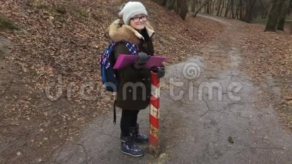 学校附近公园小路上带背包和文件夹的小女孩视频的预览图