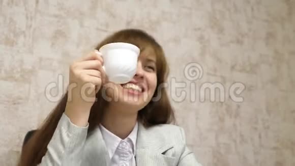 漂亮的女孩坐在办公室的椅子上聊天喝着白色杯子里的咖啡年轻女企业家休息视频的预览图