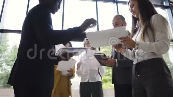 一群穿着考究的年轻商人在现代办公室里和财务文件站在一起视频的预览图