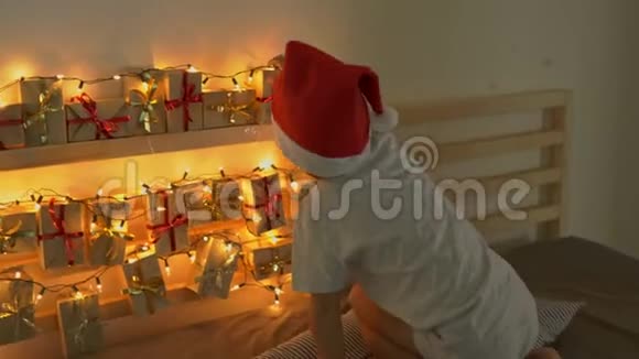 小男孩从一张挂在床上的历法里拿了一份礼物床上有圣诞灯得到的东西视频的预览图