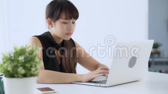 美丽的年轻自由职业亚洲女性微笑着工作在笔记本电脑和交谈客户与办公室电话视频的预览图
