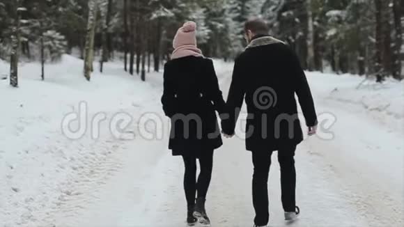 年轻美丽的夫妇在冬天的森林里散步千禧一代的男人和女人玩得很开心冬季视频的预览图