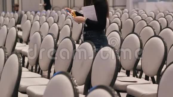 会议厅一排排灰色的椅子一位女士为特殊客人的座位编号视频的预览图