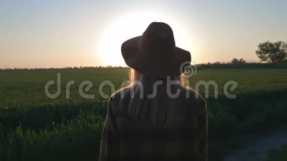 一个可爱的年轻女子旅行者或农民看日落或日出穿着格子衬衫和帽子美丽的无忧无虑视频的预览图