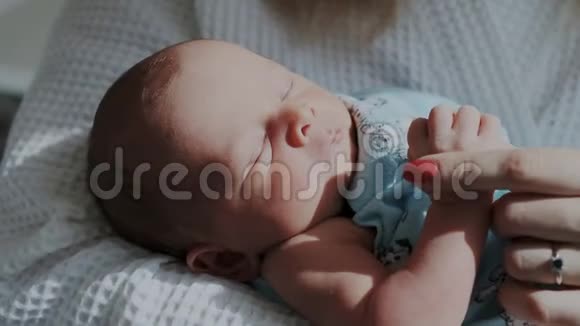 特写镜头甜蜜沉睡的小宝宝新生儿在梦中移动他的眼睛家长握着保姆的手视频的预览图