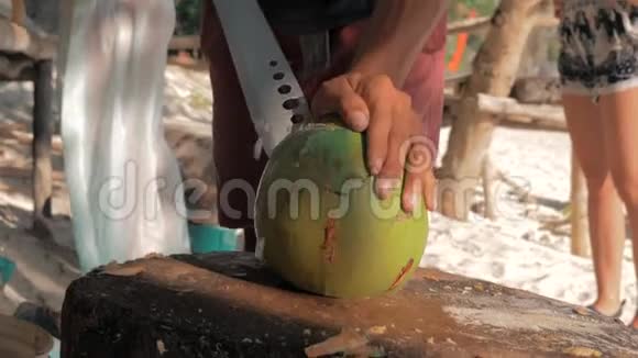特写镜头男人用一把大刀从一个年轻的新鲜椰子上切下来以获得美味的内容和多汁的饮料视频的预览图