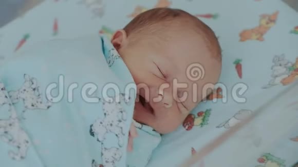 新生儿苏醒的特写镜头可爱的小宝宝在打哈欠动着手摸着脸孩子醒来后视频的预览图