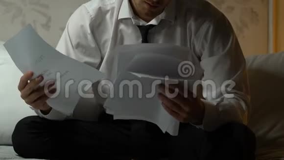 沮丧的男人坐在沙发上看银行报表破产视频的预览图