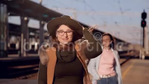 风吹落女孩帽子在火车站等火车的戴着帽子戴着眼镜的女孩视频的预览图