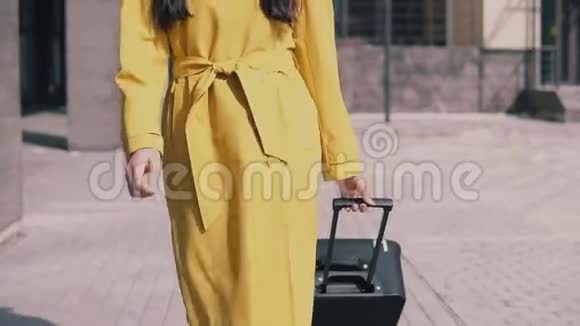 穿着黄色雨衣帽和眼镜的时髦女人带着行李微笑着视频的预览图