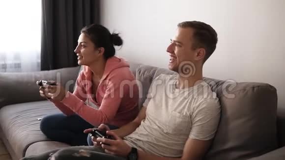 兴奋有趣的朋友或夫妇在家玩电子游戏坐在沙发上享受自己他们很棒视频的预览图