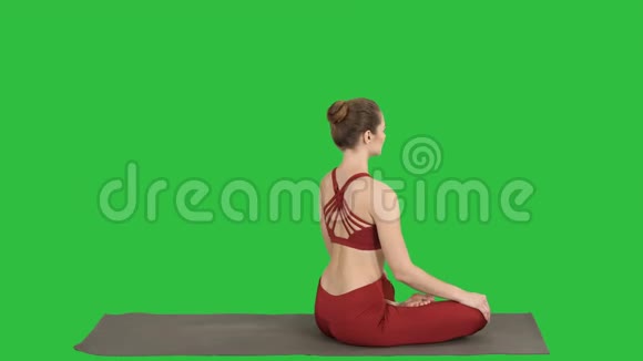运动的女人练习瑜伽莲花姿势转向相机在绿色屏幕上微笑Chroma键视频的预览图