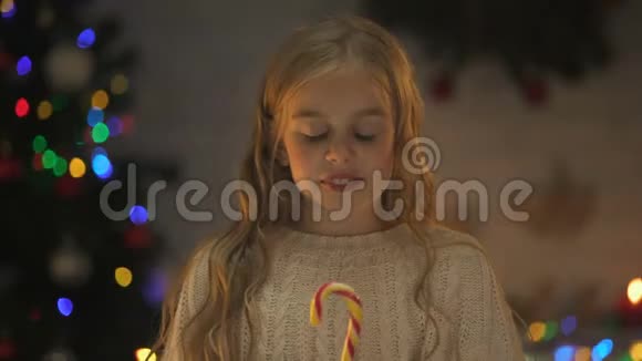 女孩吃着香甜可口的圣诞糖果梦想着礼物和庆祝活动视频的预览图