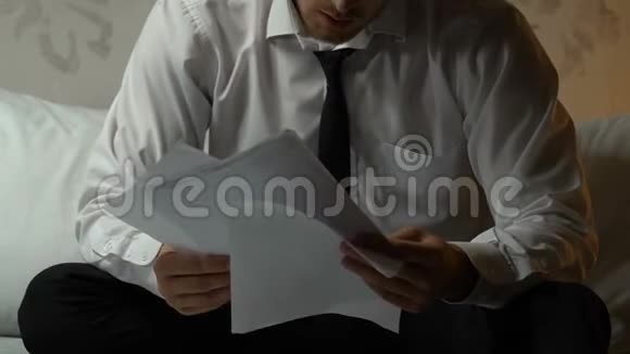 心烦意乱的男人翻阅离婚文件坐在酒店房间里分手视频的预览图