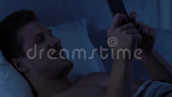 帅哥在晚上躺在床上发短信给女朋友在线约会应用程序视频的预览图