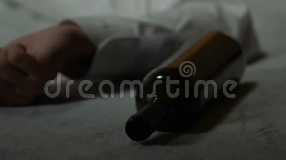 一个人试图醒来空瓶躺在床上宿醉和酗酒视频的预览图