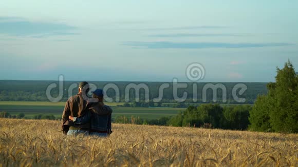 幸福的一对中年男人和女人在夕阳下的夏日傍晚在麦田上散步边说边笑视频的预览图