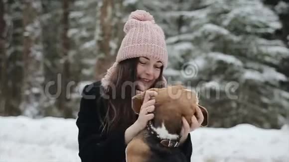 快乐的美丽的年轻女子戴着粉红色的帽子在冬天抚摸她的比格犬友谊宠物和人类候选人和候选人视频的预览图