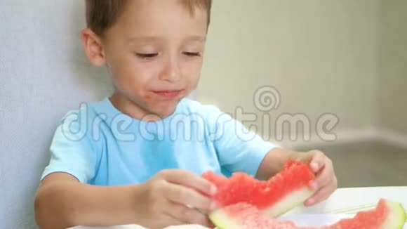 快乐的孩子坐在桌边高兴地用手吃西瓜视频的预览图