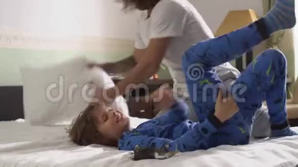 在卧室里穿着睡衣的快乐兄弟两个家伙在床上玩枕头兄弟视频的预览图