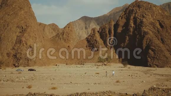 一群游客在炎热的沙漠中沿着岩石峡谷散步沙漠岩石背景埃及西奈慢运动4k视频的预览图