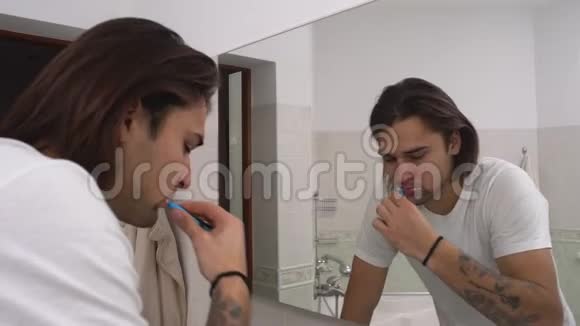 年轻人早上在浴室的镜子前刷牙早上的治疗视频的预览图