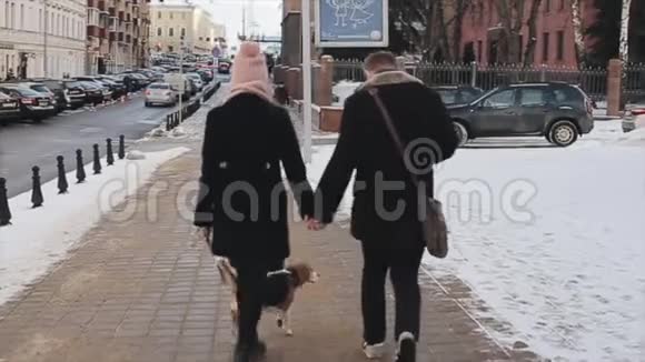 年轻时尚夫妇在街上遛狗的后景男人和女人在一起快乐小猎犬秋季视频的预览图