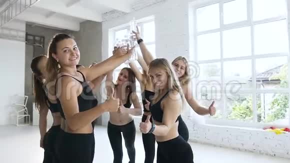 一群年轻的运动女性庆祝教练结束她们手持水瓶在有氧运动结束后显示OK视频的预览图