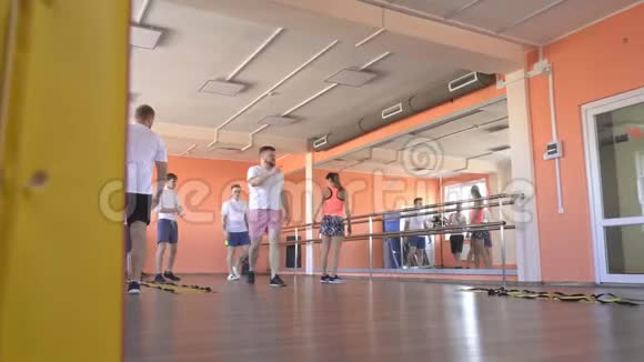 美丽的白种人女教练在一个现代化的健身中心为男性展示减肥和健康运动视频的预览图