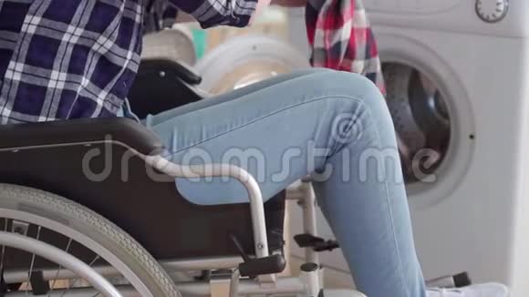 无法辨认的轮椅上的残疾妇女使用洗衣机关闭视频的预览图