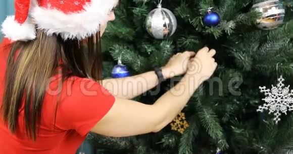 女孩把一个银色的玻璃球挂在圣诞树的树枝上视频的预览图