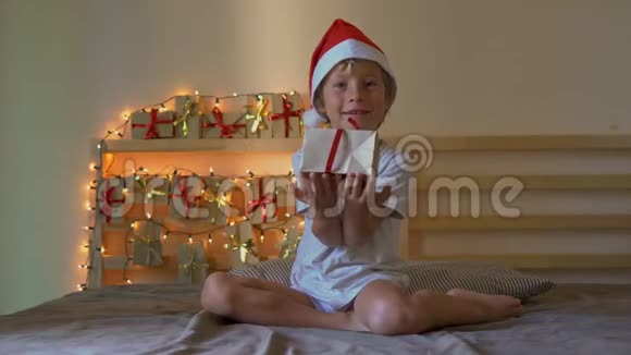 一个小男孩打开了一个礼物从一个即将到来的日历挂在一张床上上面放着圣诞灯视频的预览图