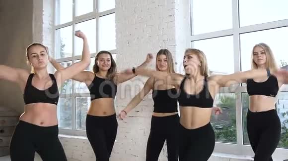 活跃的运动型女性穿着黑色运动体服站着展示二头肌集体培训概念视频的预览图