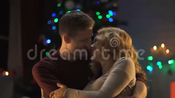 新婚夫妇在圣诞树下温柔地接吻第一次一起度假视频的预览图