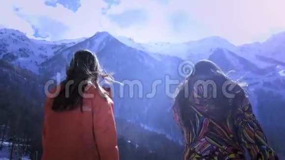 两个年轻女孩在冬天爬山微笑和挥手享冬山假期好好玩吧视频的预览图