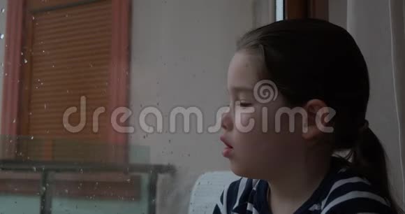 雨天一个小女孩在窗户上画画视频的预览图