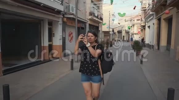 女人站在老城区的街道上为地标拍照视频的预览图