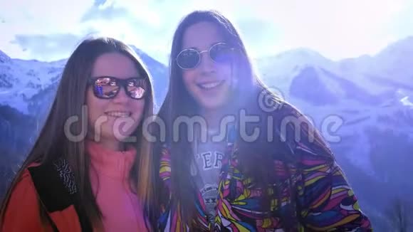 两个年轻的女孩爬进山里在背景下自拍山微笑着享受冬天的山视频的预览图