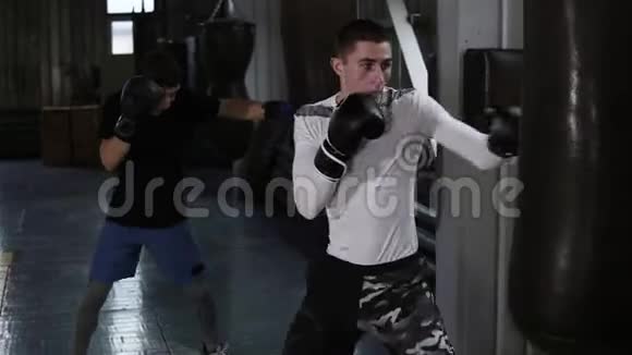 两个身穿便装的男拳击手正在打黑拳梨在拳击馆的训练过程视频的预览图