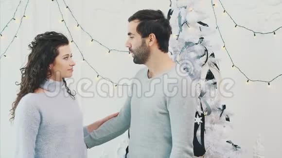 男人和女人穿着温暖的白色毛衣拥抱在光明和白色的圣诞节背景上视频的预览图